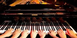 Acht Hände spielen auf einem Klavier